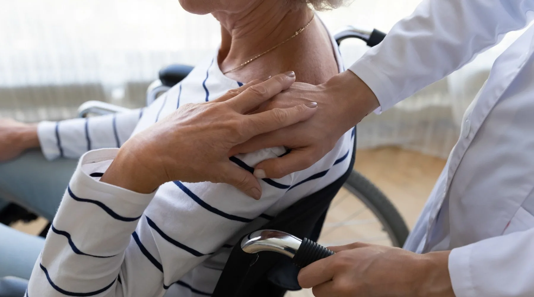 Medico che ha la mano sulla spalla del suo paziente in sedia a rotelle